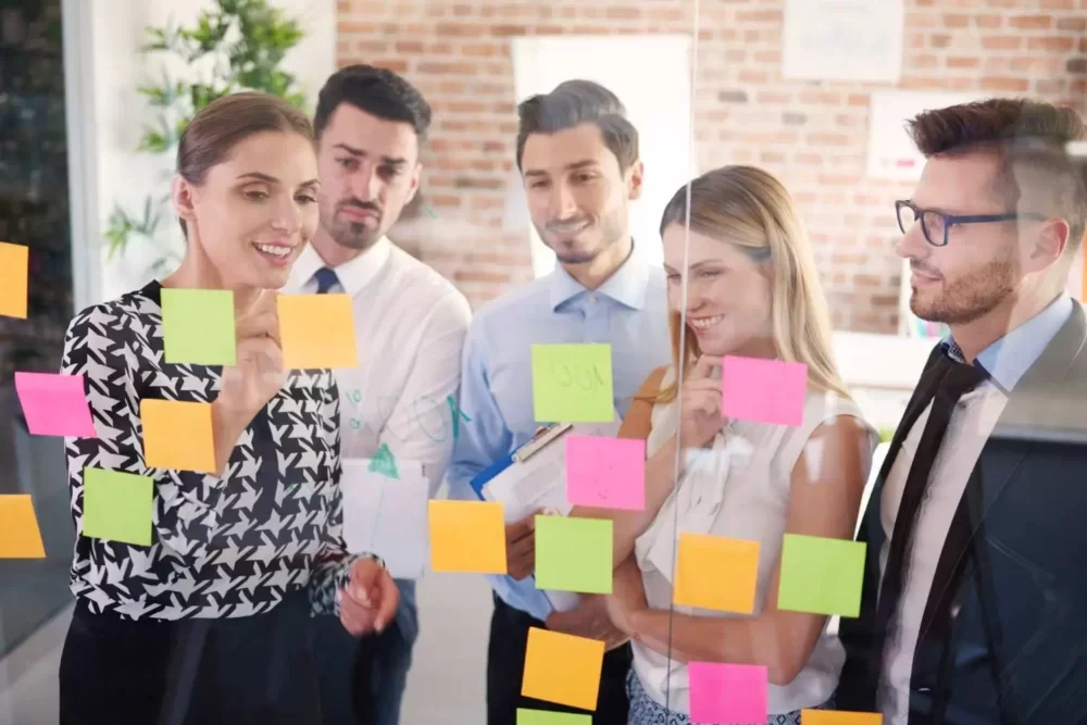 a team working in front of a board full of post its