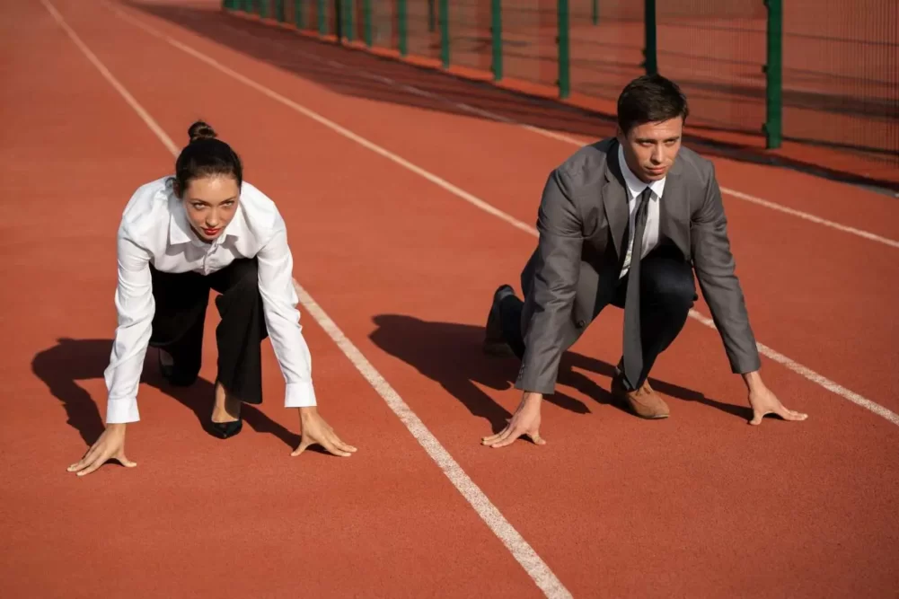 a man and woman prepared to run on an athletics running track