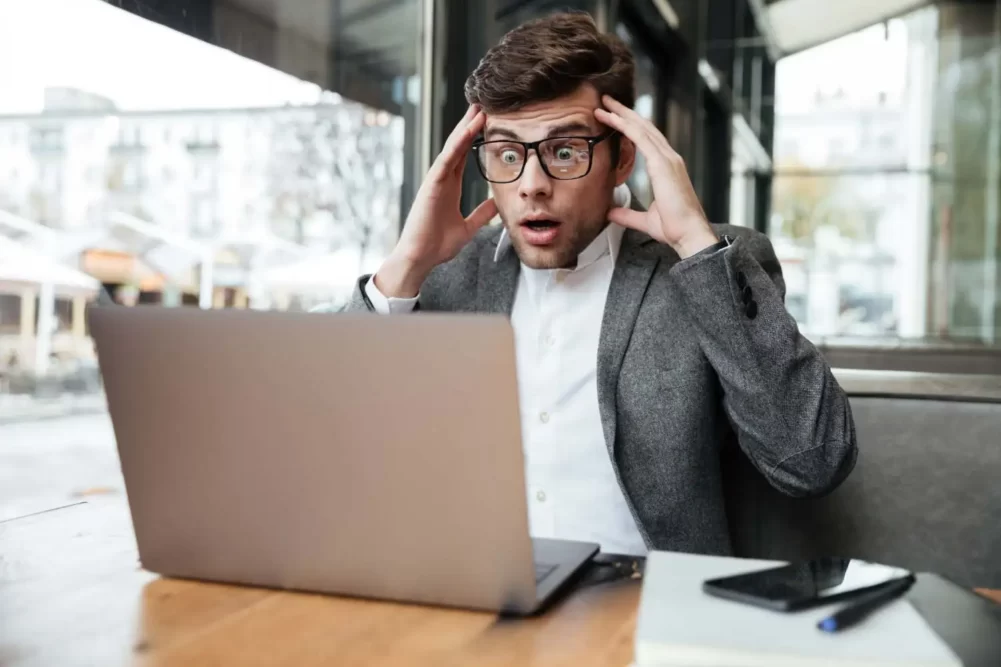 a scared man looking at his laptop