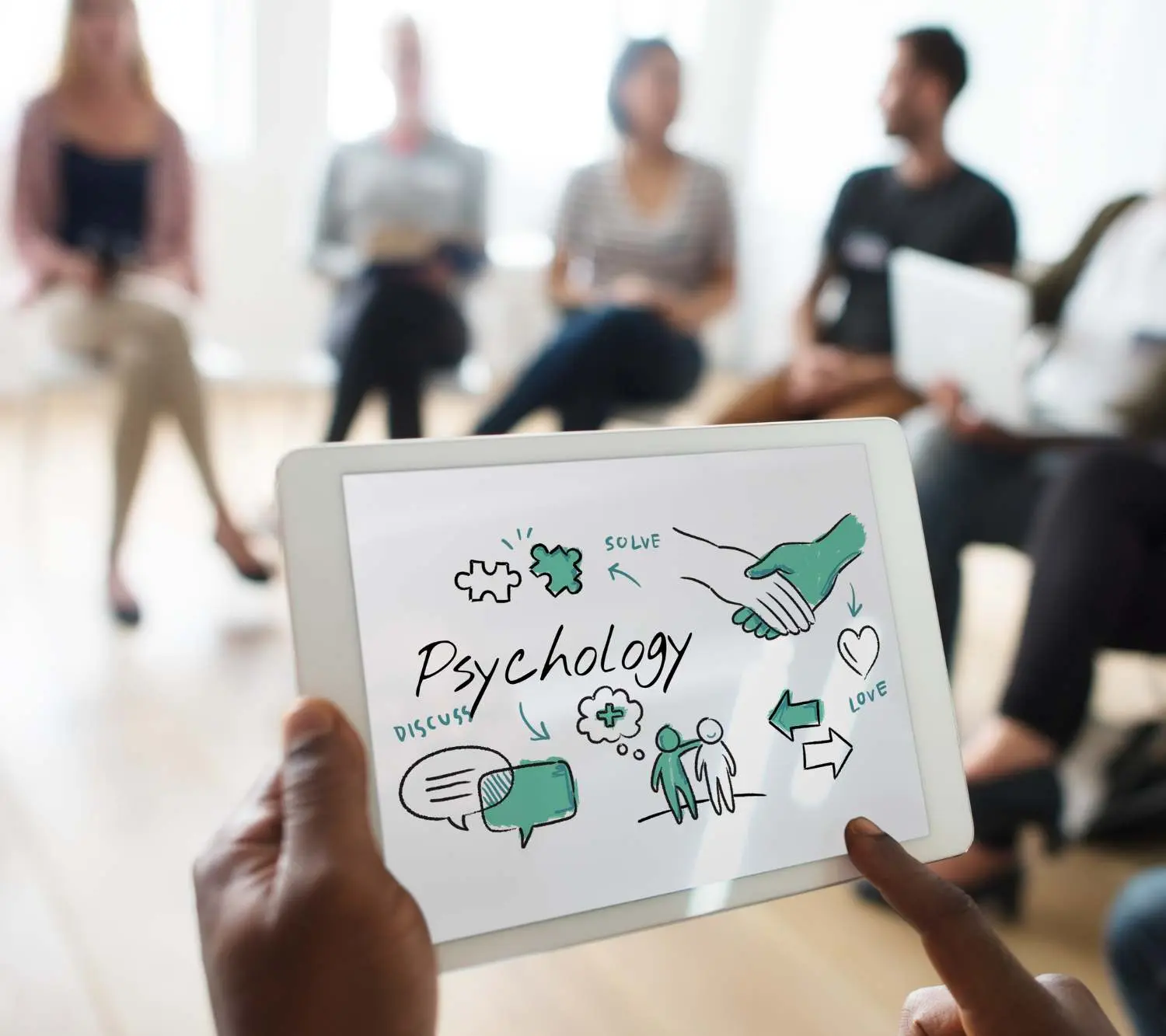 un grupo de personas sentadas en círculo y una tableta escrita psicología