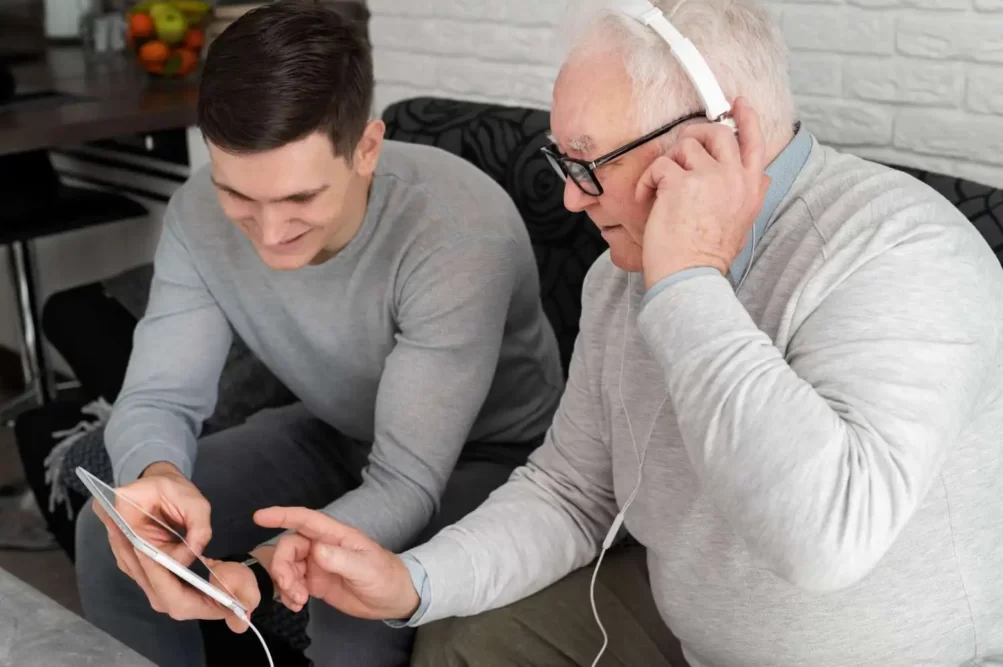 un uomo anziano che impara a usare i dispositivi elettronici uno con un giovane