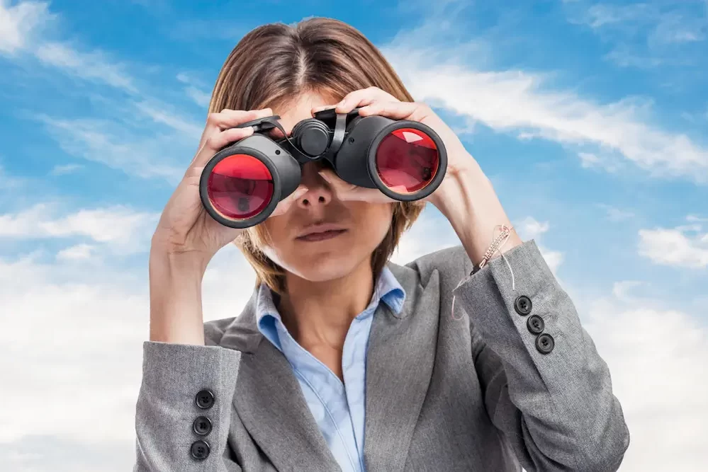 headhunter: a woman using binoculars looking for a talent