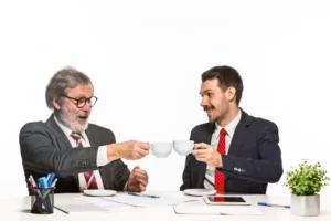 differences between mentoring and coaching: two men toasting a cup of coffee